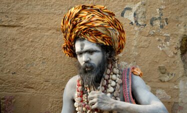 Portrait of a traditional sadhu with painted face and colorful turban in Varanasi, India.