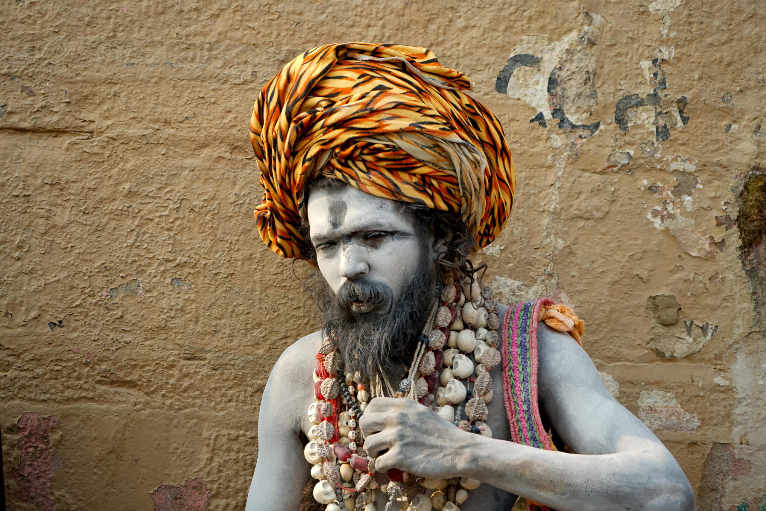 Portrait of a traditional sadhu with painted face and colorful turban in Varanasi, India.