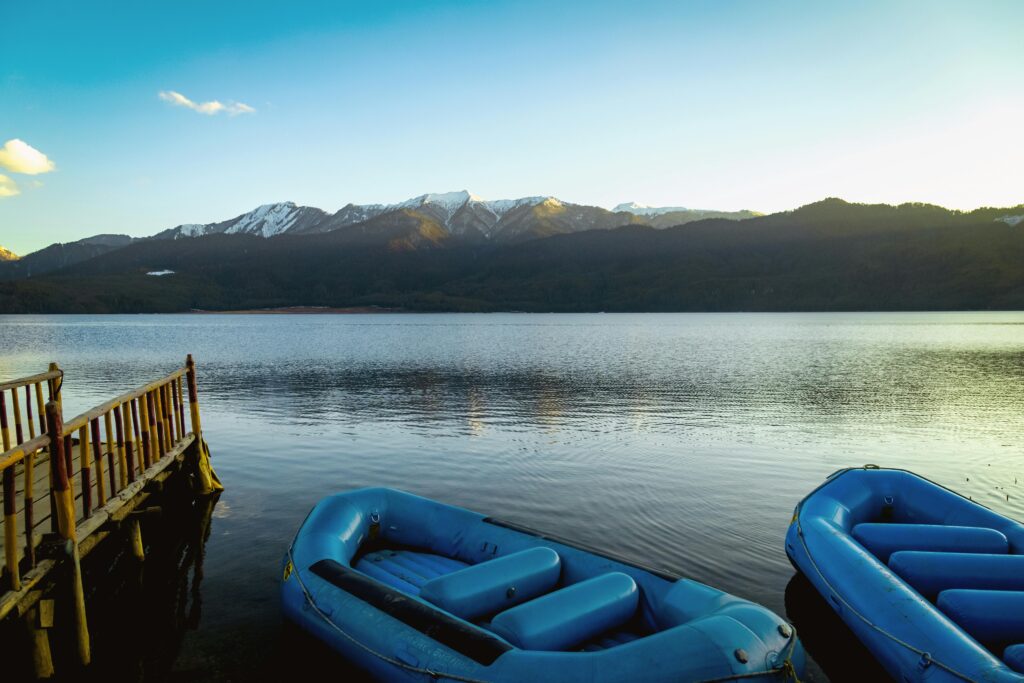 Peaceful scene of Rara Lake with blue inflatables and mountains in Nepal.