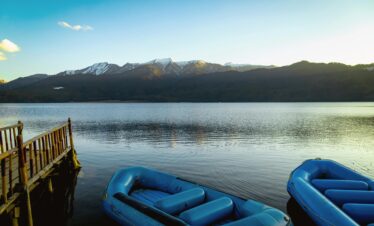 Peaceful scene of Rara Lake with blue inflatables and mountains in Nepal.